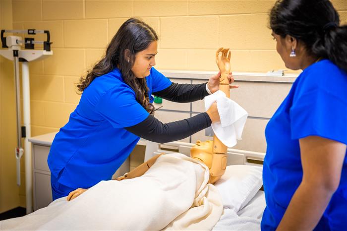 Two student nurses practicing on a dummy patient